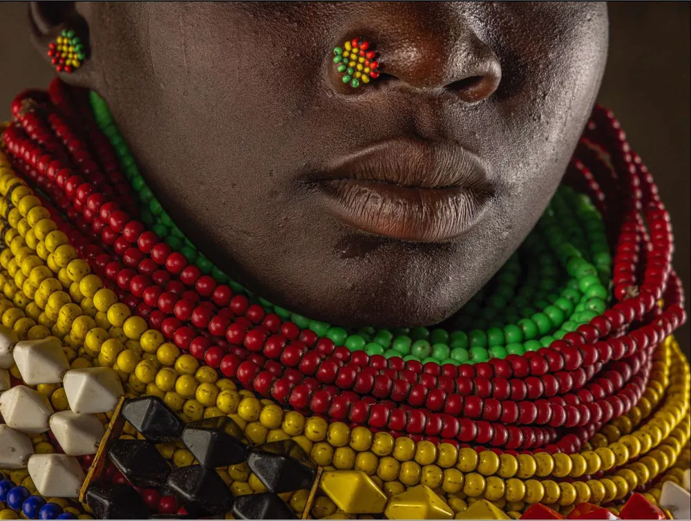 Rostro de una persona karo con collares de cuentas de colores
