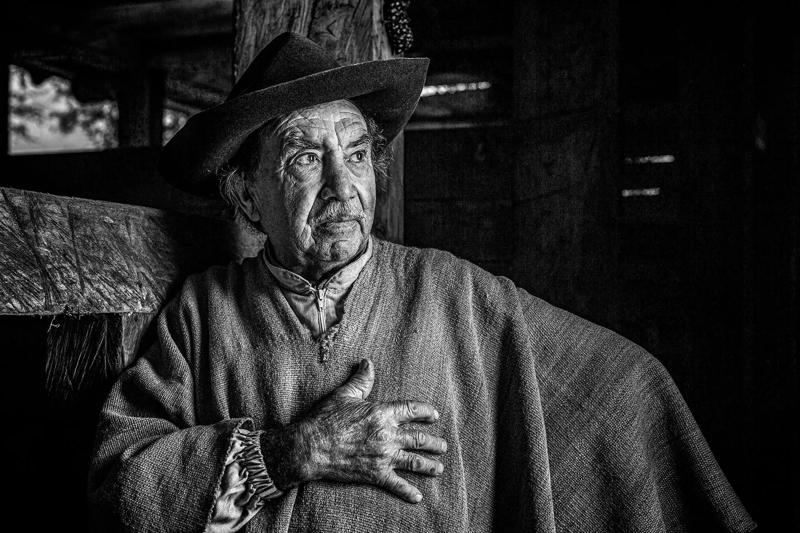 Hombre mayor con sombrero en un interior, en blanco y negro