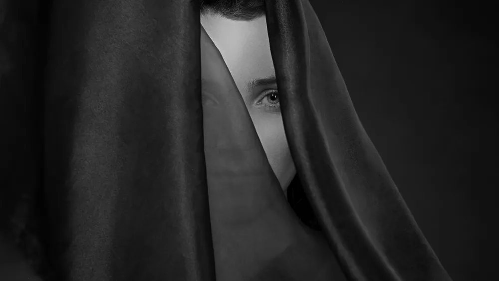 Rostro cubierto por un manto negro, en blanco y negro
