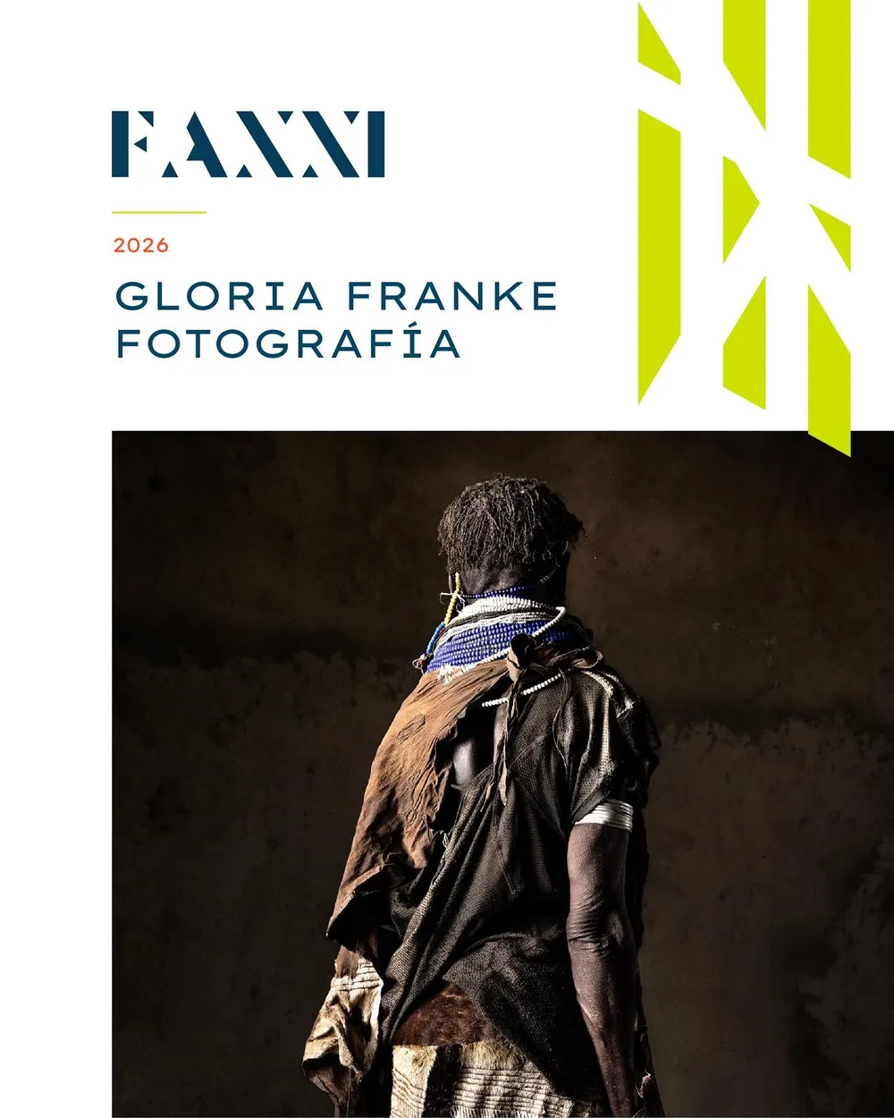 Portada de FAXXI 2026, Gloria Franke Fotografía: persona de espaldas con un manto oscuro y collar de cuentas azules sobre un muro en penumbra