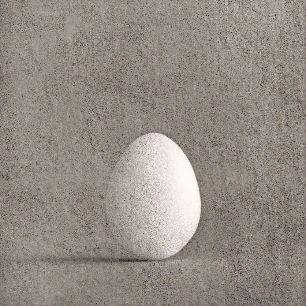 Huevo blanco sobre fondo gris claro texturado