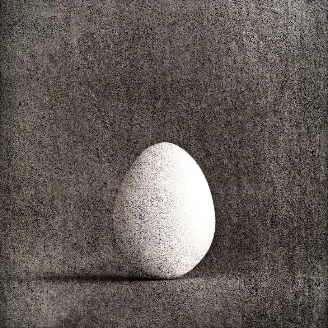 Huevo blanco sobre fondo gris oscuro texturado