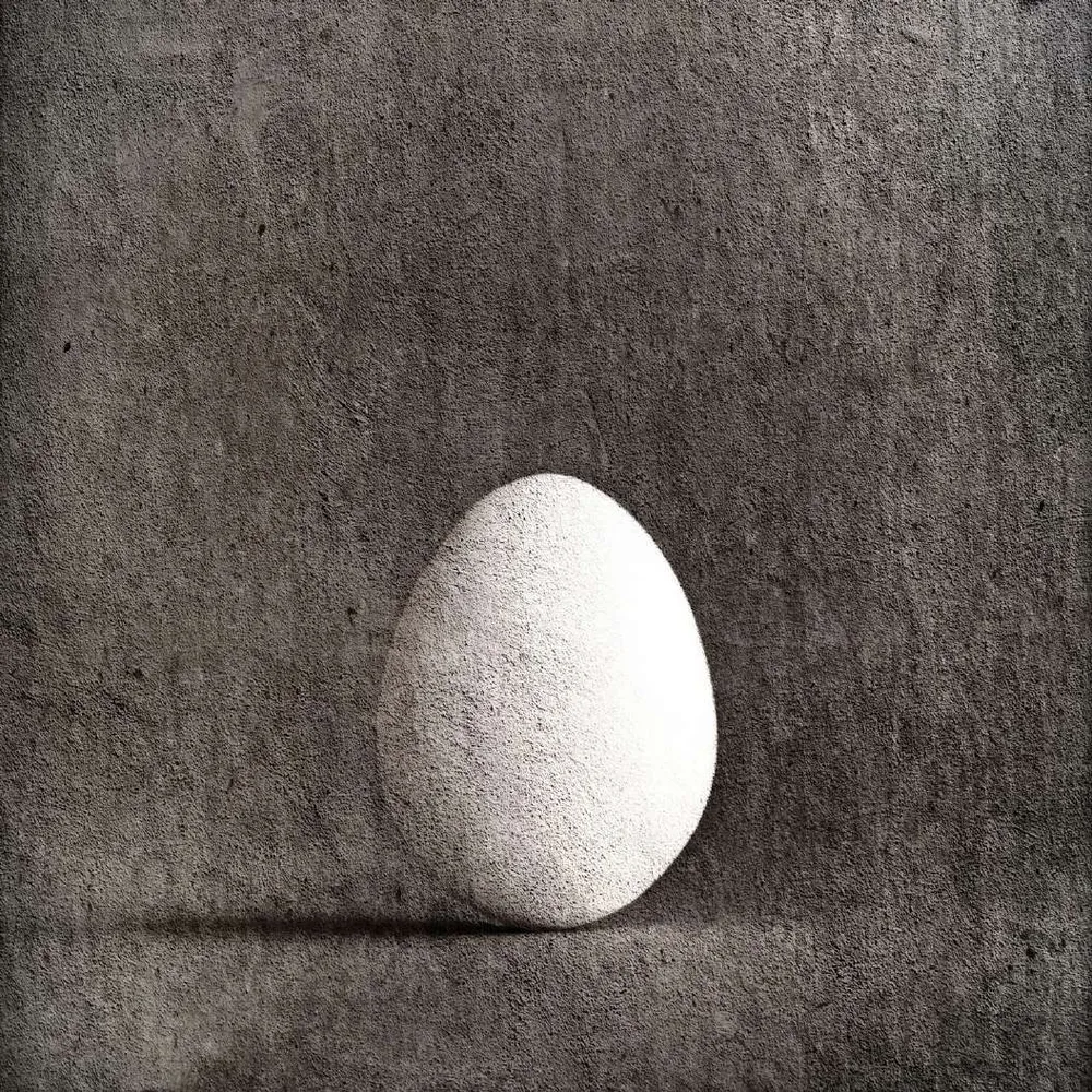 Huevo blanco sobre fondo gris oscuro texturado
