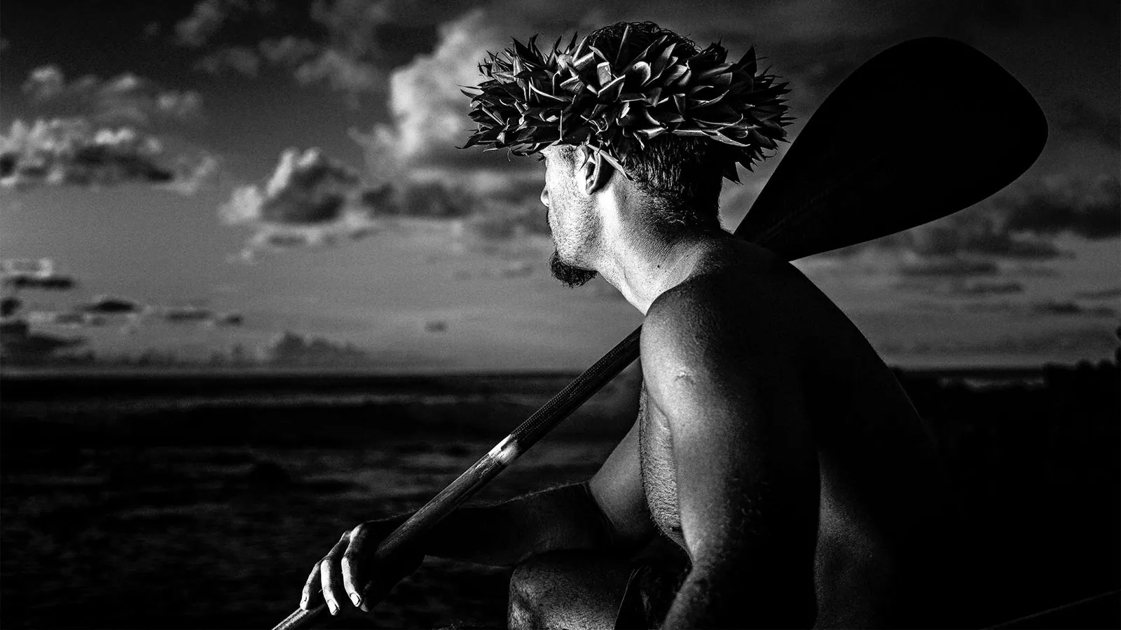 Hombre rapa nui con un remo frente al mar, en blanco y negro