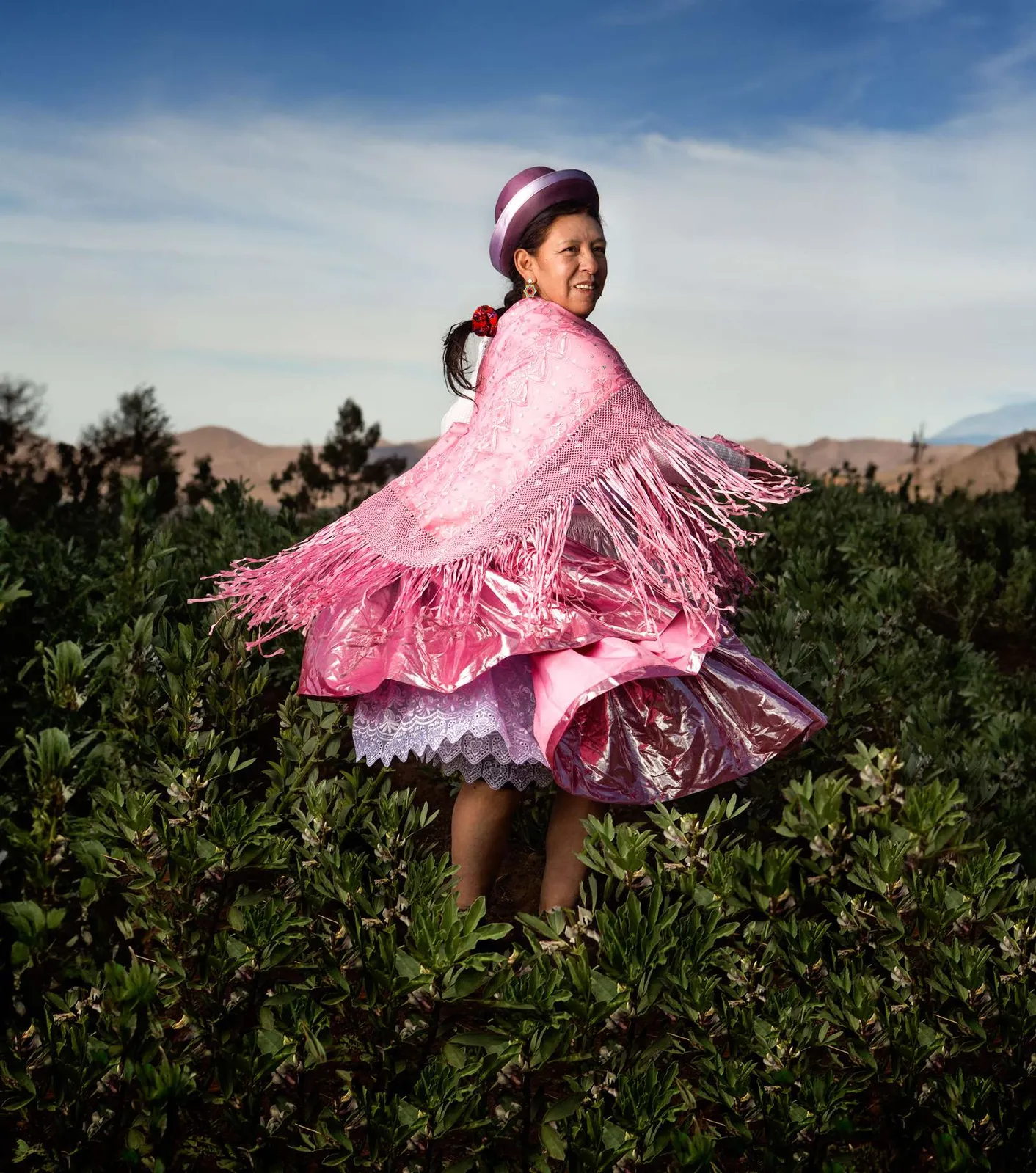 Niña con pollera rosada girando en un campo verde