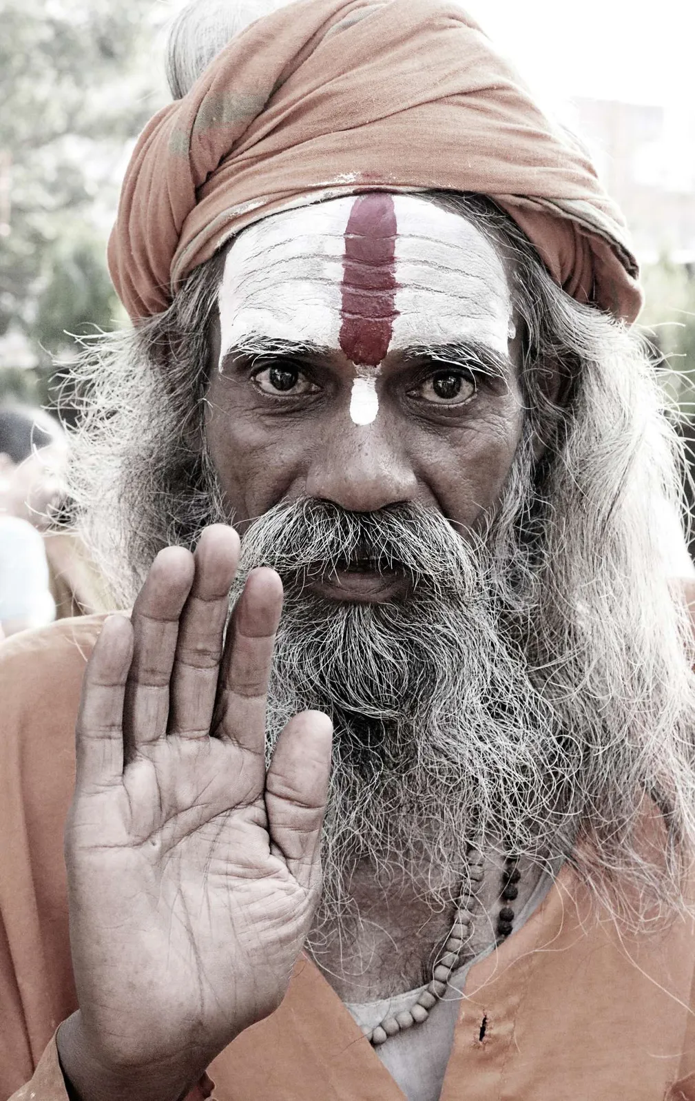 Sadhu de barba blanca y pintura en la frente levantando la palma de la mano