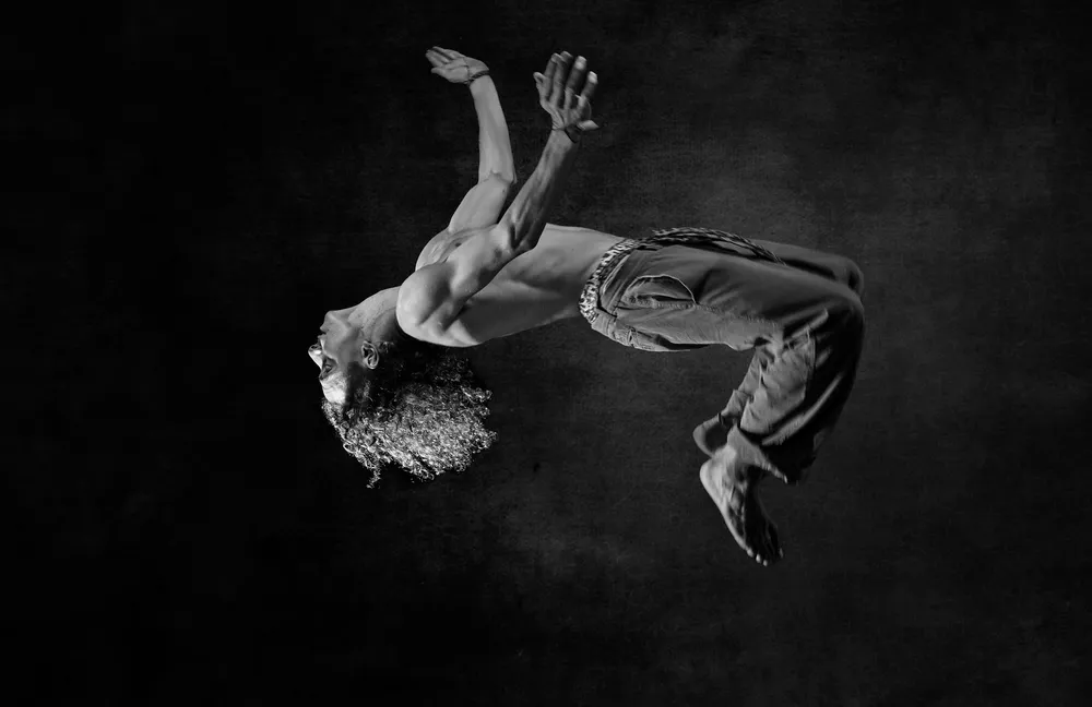 Cuerpo suspendido en el aire sobre fondo oscuro, en blanco y negro