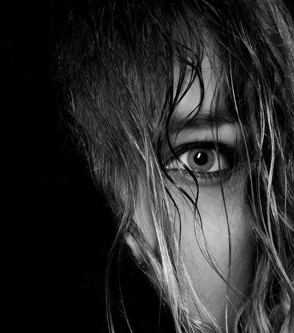 Ojo de una mujer entre mechones de pelo, en blanco y negro