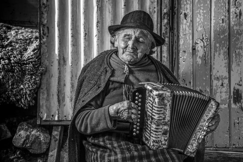 Hombre mayor con sombrero tocando el acordeón, en blanco y negro