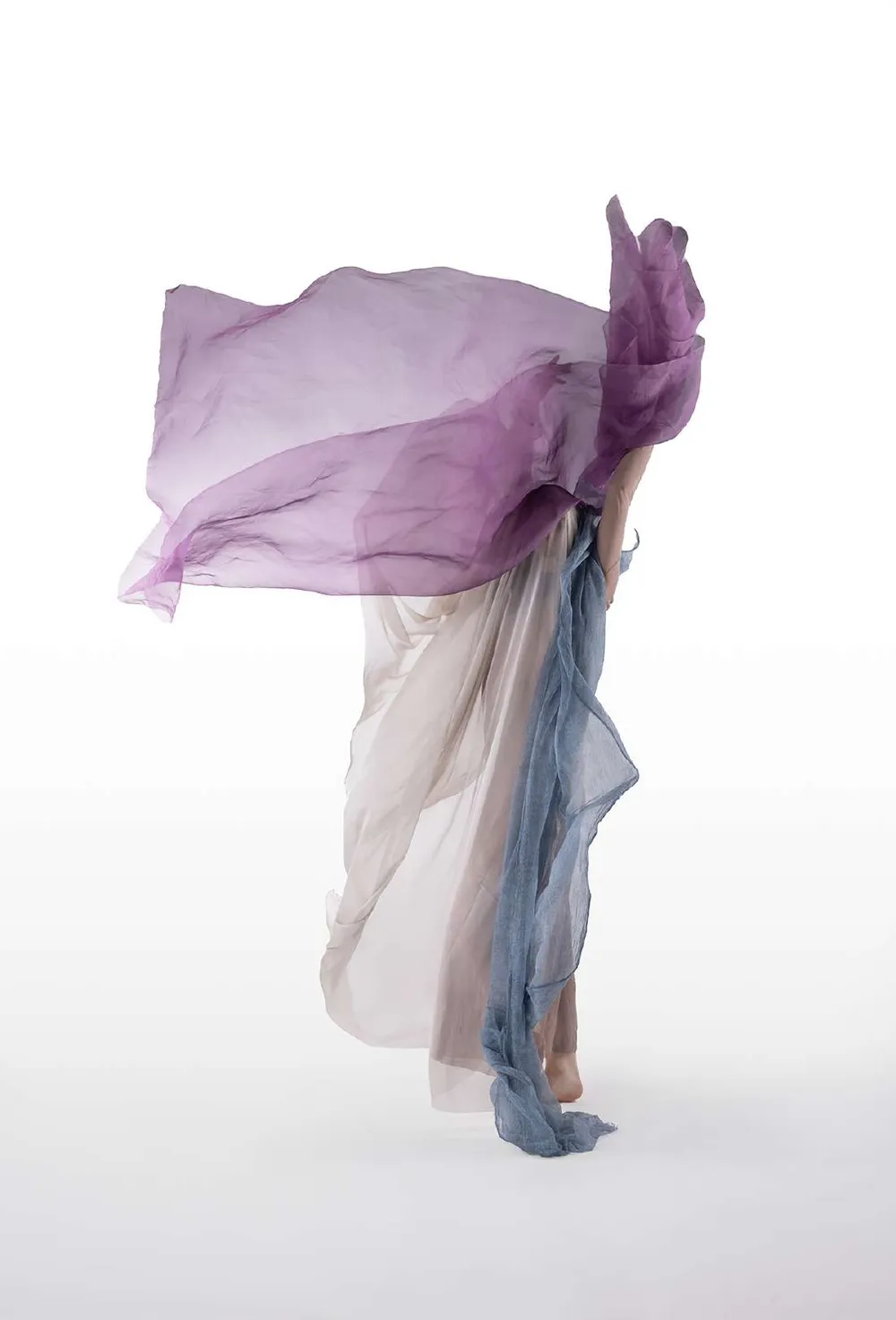 Modelo con una tela violeta desplegada sobre la cabeza, sobre fondo blanco