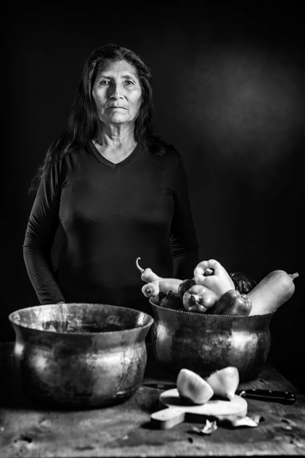 Mujer de pie junto a vasijas, en blanco y negro
